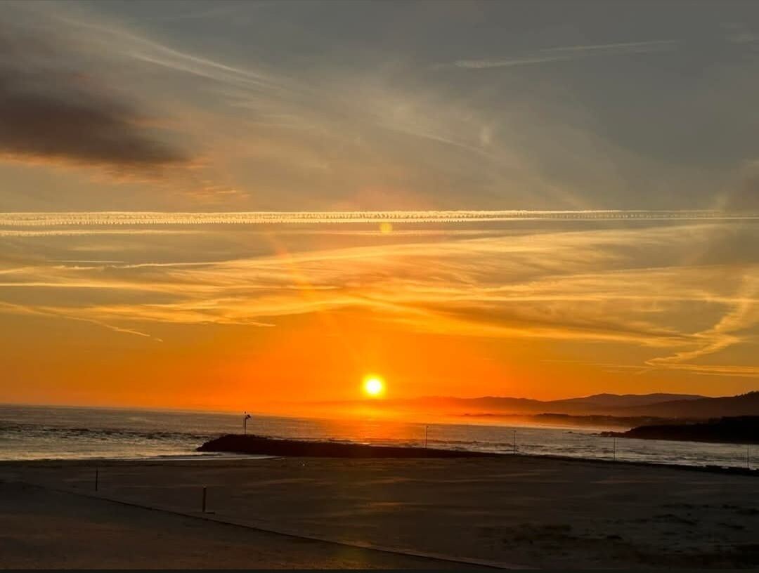 Een zonsondergang boven een strand met een heldere lucht en een verafgelegen stadshemel.