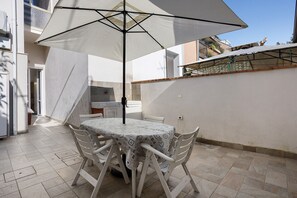 A patio with a table and chairs, an umbrella, and a tiled floor. - Comfortable Apartment Steps from the Sea - Marina di Carrara (Marina di Carrara)
