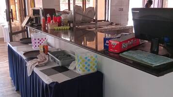 Una habitación de hotel con una mesa larga, una cama, una ventana y una puerta.