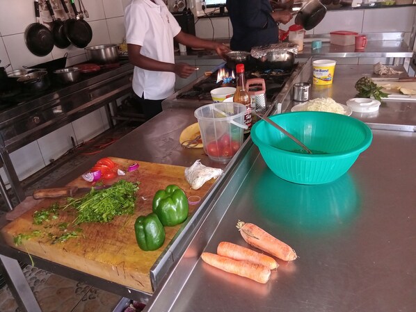Una cocina con tabla de cortar, verduras y utensilios de cocina.