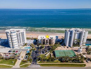 A coastal hotel with multiple high-rise buildings, a central building with a star symbol, and a beach view. - Sandcastle 401 (New Smyrna Beach)