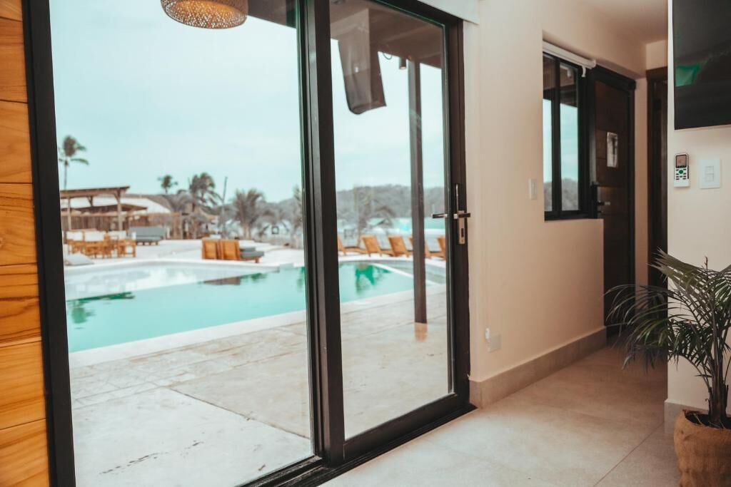 A modern hotel room with a large sliding glass door leading to a pool area.