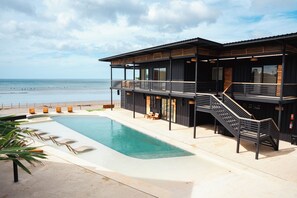 Una piscina al aire libre, sillones reclinables de piscina