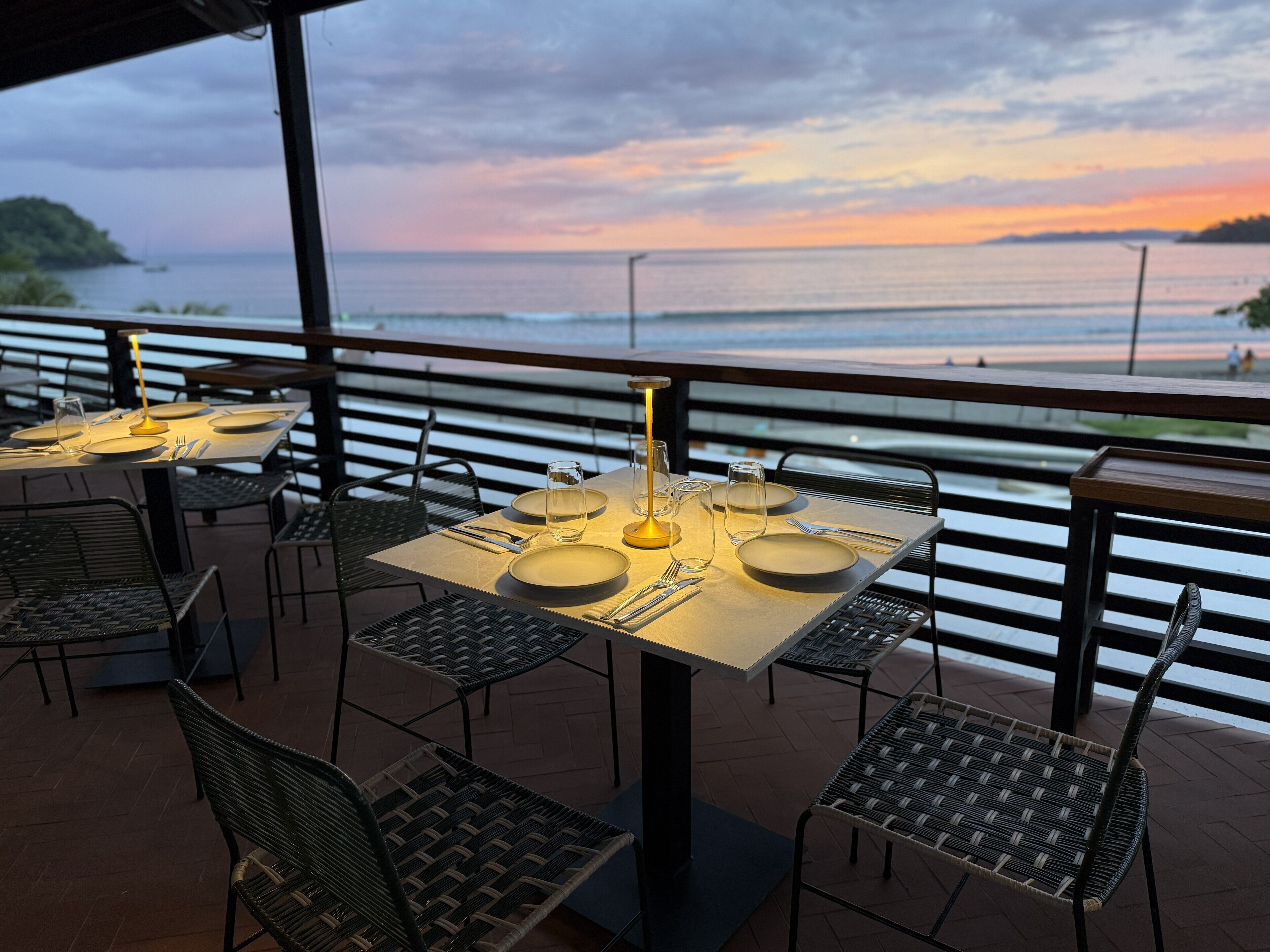 A restaurant with tables set for dining, overlooking a body of water.