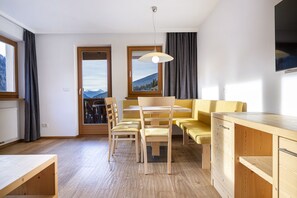 Et moderne køkken med træskabe, et spisebord med stole og udsigt til bjerge gennem vinduerne.