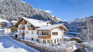 A snow-covered mountain resort with multi-story buildings, a stone wall, and a clear sky. - 1012A Apartments Monica (Santa Cristina Valgardena)