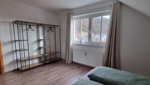 Een kamer met een bed, een kledingkast, een radiator en een raam met gordijnen.
