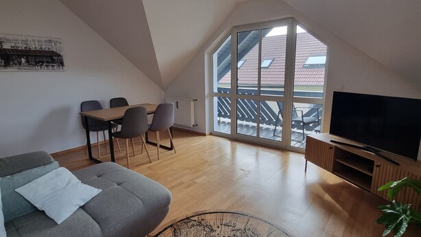 Een modern loft appartement met een eethoek, een groot raam en een flatscreen televisie.