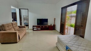 Una sala de estar con sofá, televisión, aparador de madera y colchón.