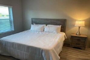 Quarto com cama, mesa de cabeceira e abajur.