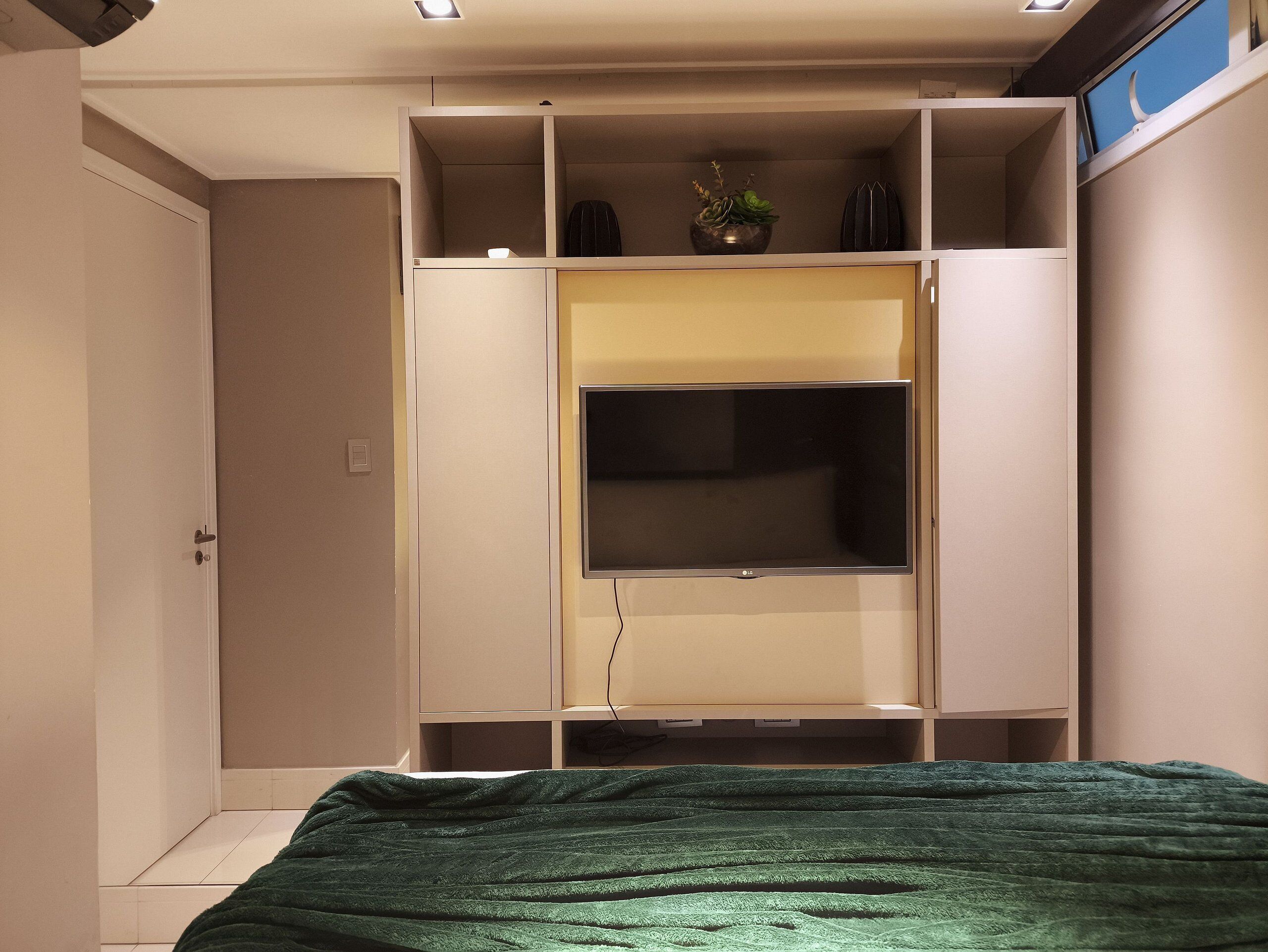 Un dormitorio con cama, armario y televisor.