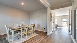 Une salle à manger spacieuse avec une table et des chaises en bois, un tapis à motifs et un couloir menant à un balcon.