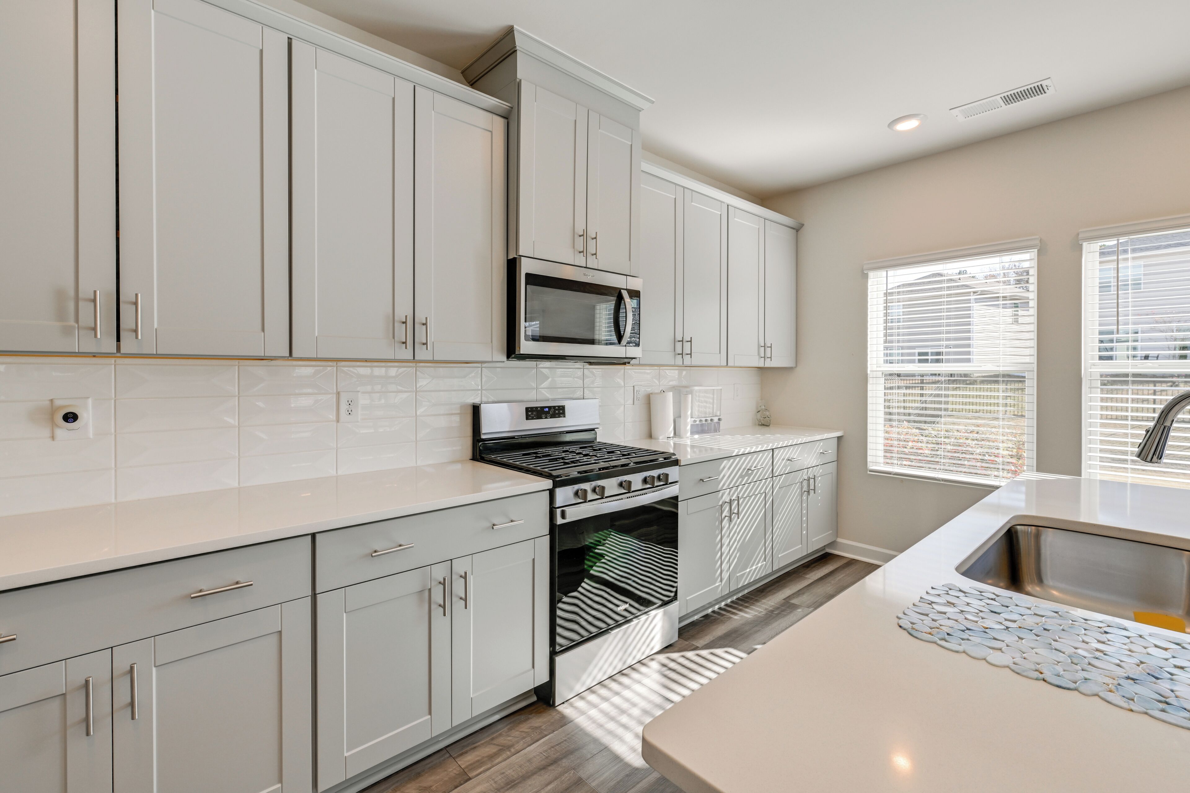 A modern kitchen with white cabinets, a stainless steel sink, and a built-in oven.