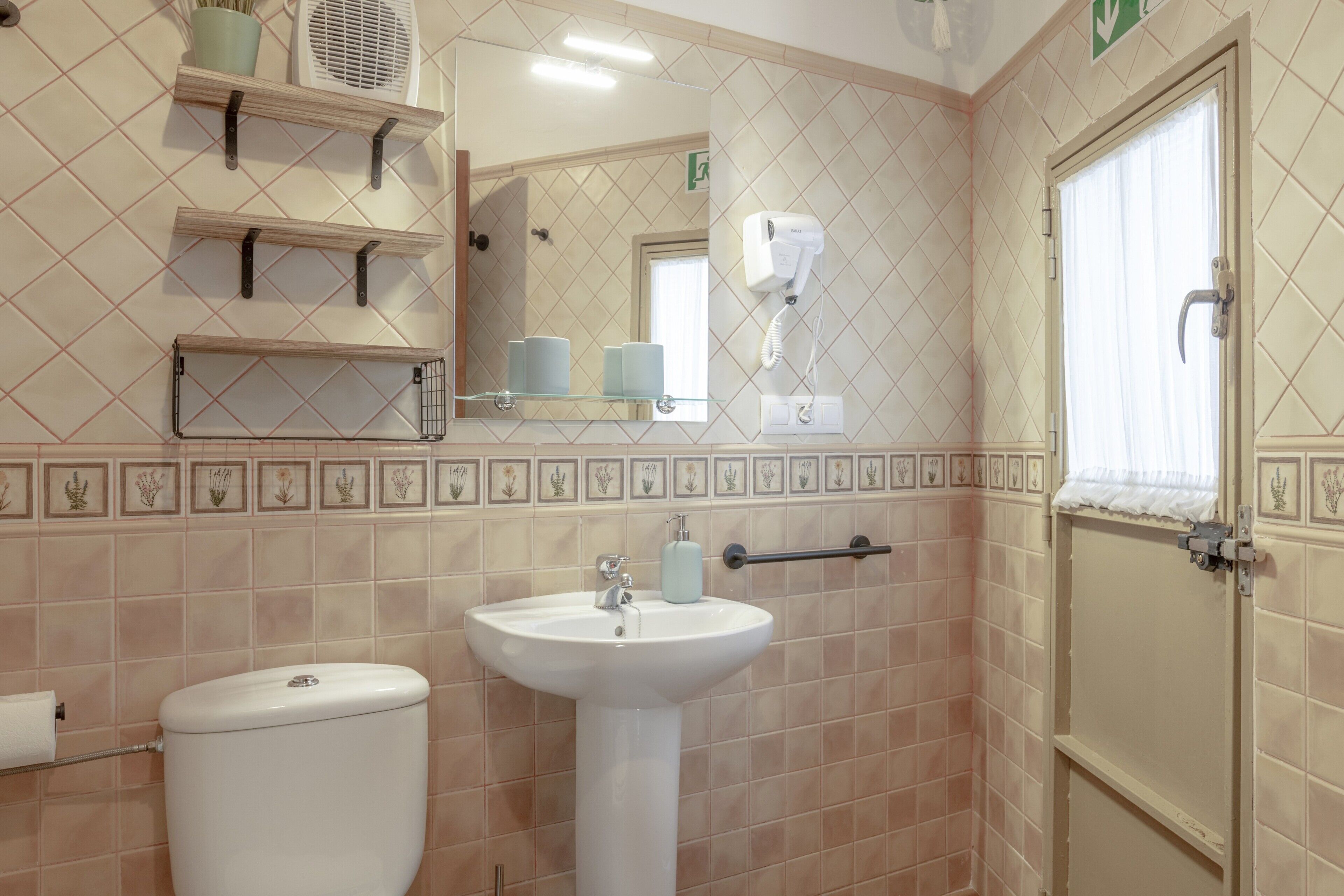 A bathroom with a toilet, sink, towel rack, and a hand dryer.