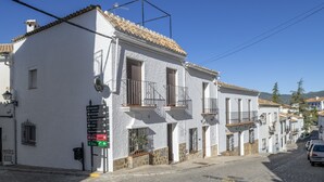 A white building with balconies, a street sign, and a cobblestone road.