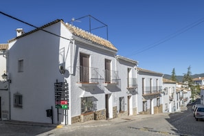 A white building with balconies, a street sign, and a cobblestone road. - Apartment 'Los Cuatro Vientos' with Wi-Fi (Zahara de la Sierra)