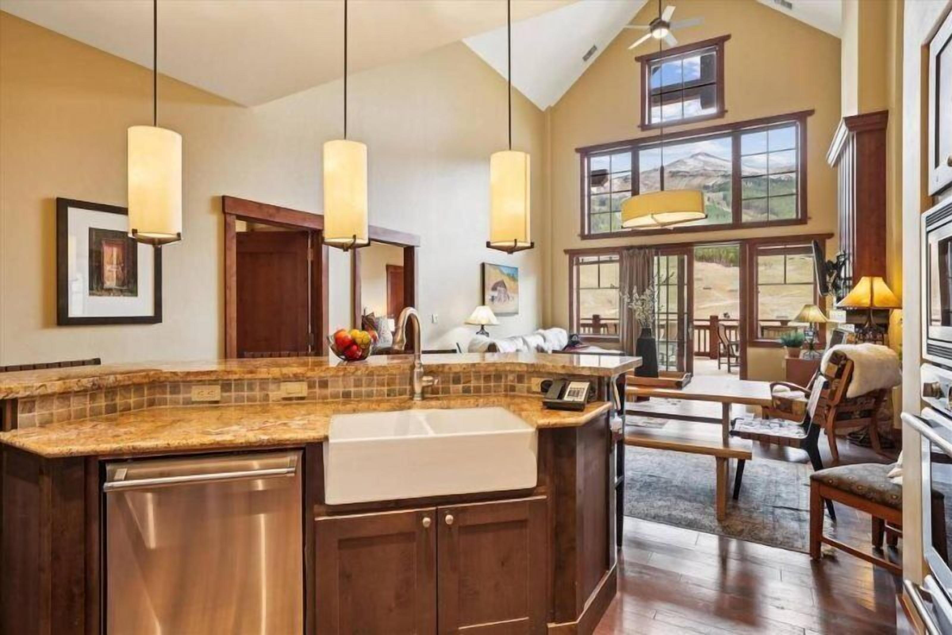 A spacious kitchen with a large island, wooden cabinets, and pendant lighting.
