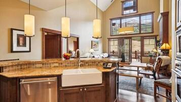A spacious kitchen with a large island, wooden cabinets, and pendant lighting.