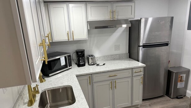 A modern kitchen with white cabinets, stainless steel appliances, and a granite countertop. - Near DC 5 bdrm 4.5 bth 11 beds 2 kitchens &parking (Silver Spring)