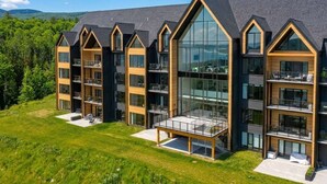 Ein modernes, mehrgeschossiges Hotel mit großen Fenstern, Balkonen und einer gepflegten Rasenfläche vor der Fassade.