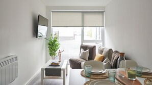A modern living room with a sofa, coffee table, and dining area. - Student Only The Quarry (Falmouth)