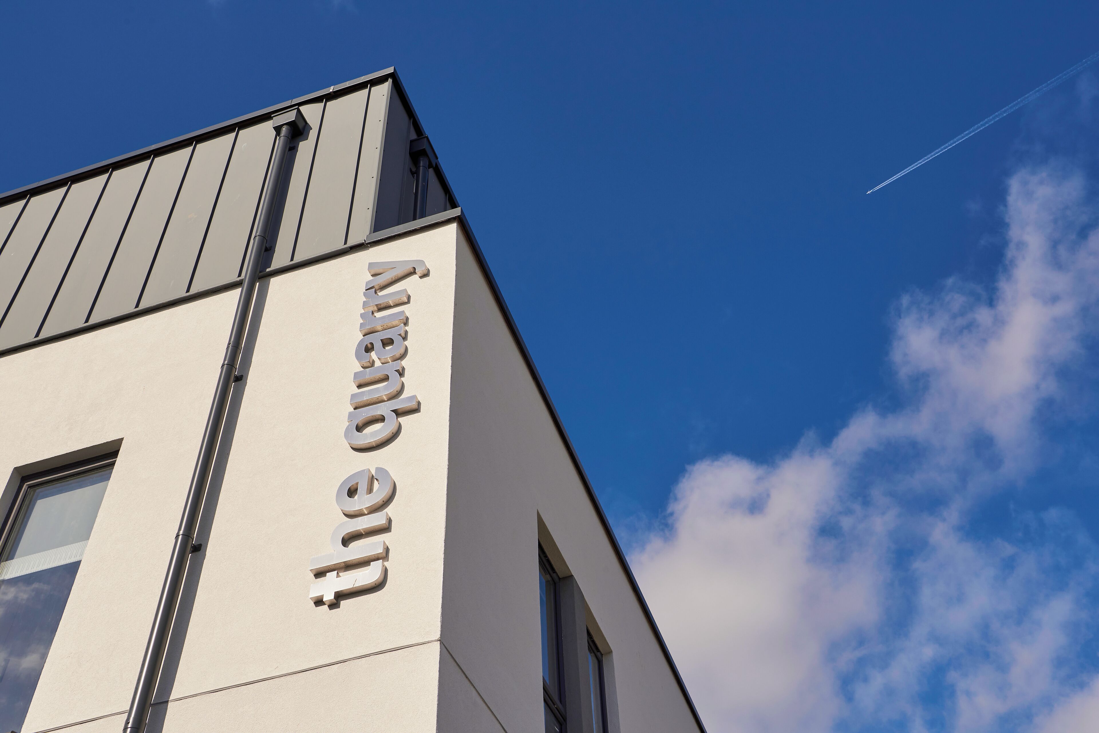 A building with a modern architectural design, featuring a prominent sign on the side.