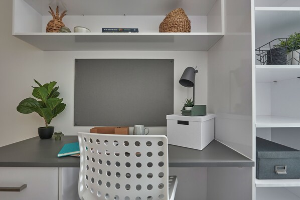 A modern workspace with a desk, chair, shelves, and a potted plant. - Student Only The Quarry (Falmouth)