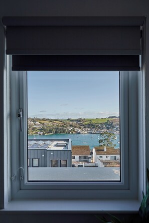 A view from a window with a roller blind, overlooking a coastal town with buildings and boats. - Student Only The Quarry (Falmouth)