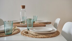 A dining table set with plates, glasses, and a bottle. - Student Only The Quarry (Falmouth)