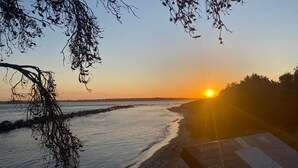 Ein Sonnenuntergang über einem Strand mit felsiger Küste und einem Schild.