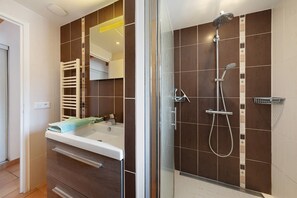 Ein modernes Badezimmer mit einer Duschkabine aus Glas, einem weißen Waschbecken und einem Handtuchhalter.