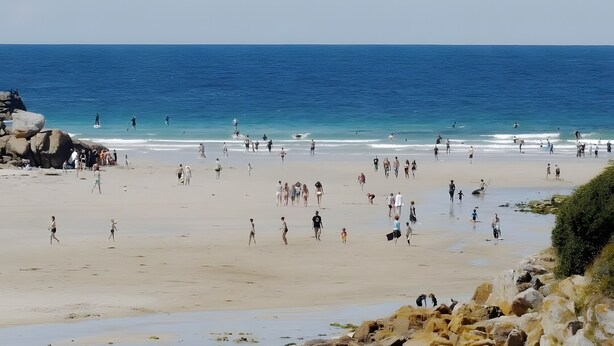 A beach with people walking, a kite in the sky, and the ocean in the background. - Ground-Floor Stone Cottage Between Countryside and Sea (Landunvez)