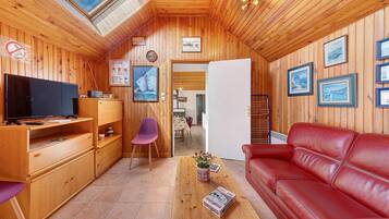Ein gemütliches Holzinterieur mit Fernseher, einer roten Ledersofa und gerahmten Bildern an den Wänden.
