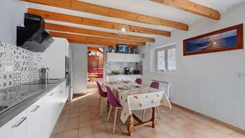 Una cocina moderna con vigas de madera, un comedor con mesa dispuesta para cuatro personas y una isla de cocina con pileta y estufa.