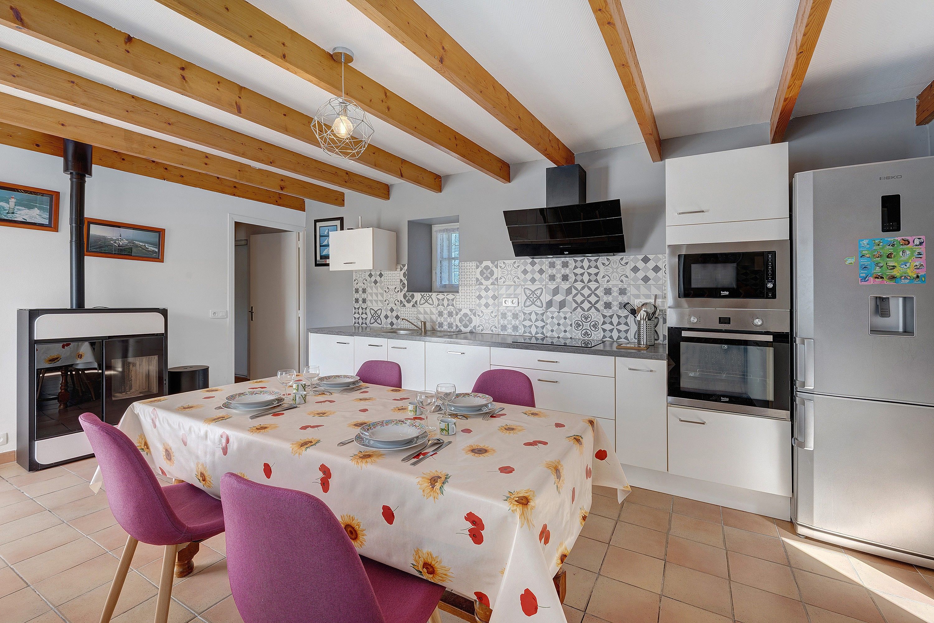 Een moderne keuken met een eethoek, met een inbouwoven, magnetron en een grote koelkast.