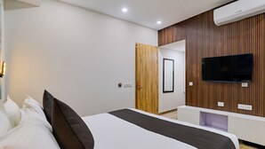 Habitación de hotel moderna con una cama grande, un televisor montado en la pared y un diseño de paneles de madera.