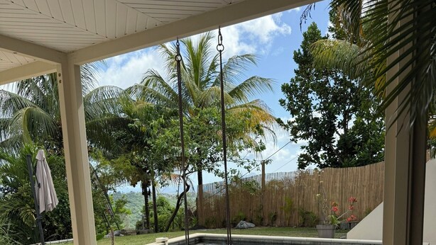 A covered outdoor area with a pool, seating, and a view of the surrounding landscape. - A small, contemporary home, perfect for families: Villa Nathoun's. (Rivière-Salée)