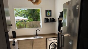 A modern kitchen with a stainless steel refrigerator, a washing machine, and a window with a view of greenery. - A small, contemporary home, perfect for families: Villa Nathoun's. (Rivière-Salée)