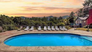 Ein Swimmingpool mit Liegestühlen und Blick auf die Berge bei Sonnenuntergang.