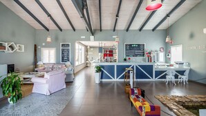 Un grand espace de vie comprenant un comptoir de cuisine, des coins salon et un tableau affichant le menu.