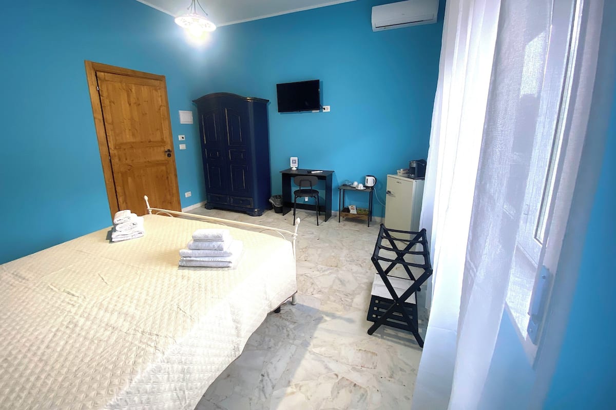 A bedroom with a bed, a TV, a desk, and a wardrobe.