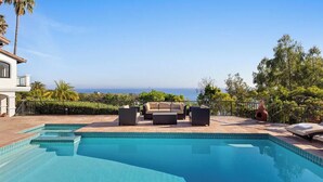 A swimming pool with a view of the ocean, outdoor furniture, and a palm tree. - Villa Costera - Tree-lined Tranquility: 3-level Entertainer's Dream (Malibu)