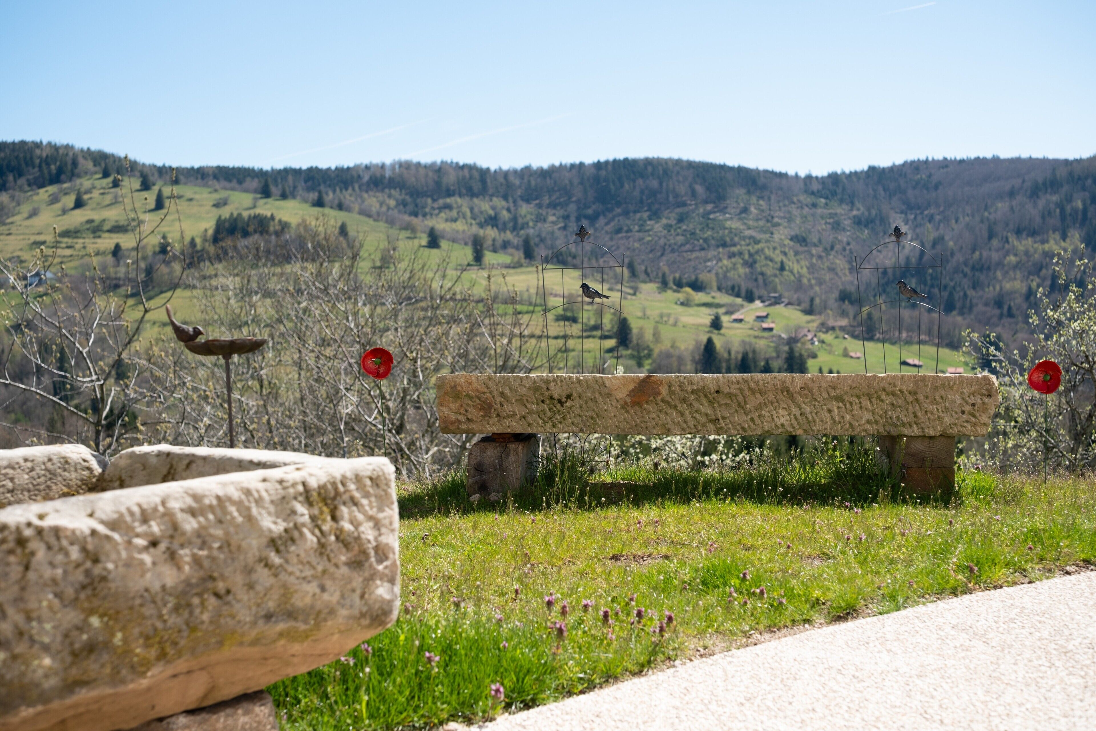 Un banco de piedra en un área con césped, con vistas a un paisaje montañoso al fondo.