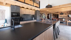 Une cuisine moderne dotée d’un îlot central, d’appareils électroménagers intégrés et d’un plan de travail supérieur en bois.