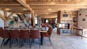Un espace repas doté d’un plafond en bois, d’un pilier en pierre et d’une cheminée.