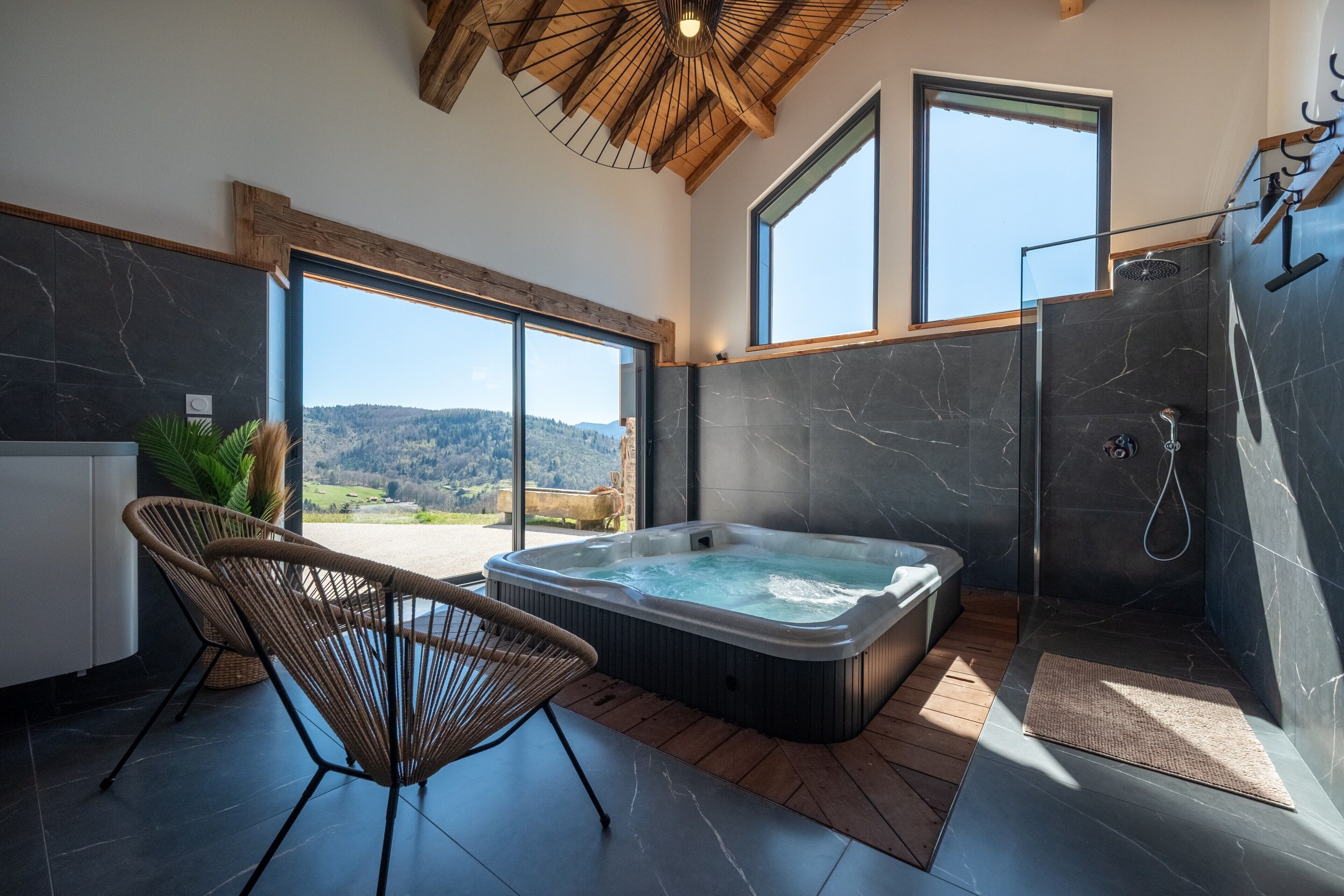 Un baño moderno con bañera de hidromasaje, ducha y ventanas amplias que ofrecen vistas al exterior.
