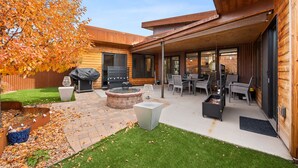 Eine moderne Außenpatio mit Feuerstelle, Sitzgruppe und Grill.