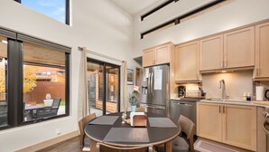 Eine moderne Küche mit Holzausstattung, einem Edelstahlkühlschrank und einer Essecke mit rundem Tisch und Stühlen.