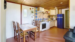 Une cuisine compacte avec des meubles en bois, une table à manger avec des chaises, un réfrigérateur et un four à micro-ondes.