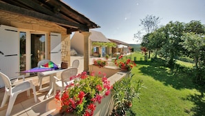 A patio with outdoor furniture, a table, and potted plants. - Gite Charly: Private Terrace, Shared Garden, Pool & Wi-Fi in Salignac Eyvigues (Salignac Eyvigues)